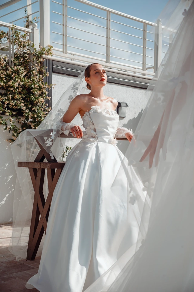 White bridal gown with large floral details around the off-the-shoulder neckline and a full skirt., photo 1